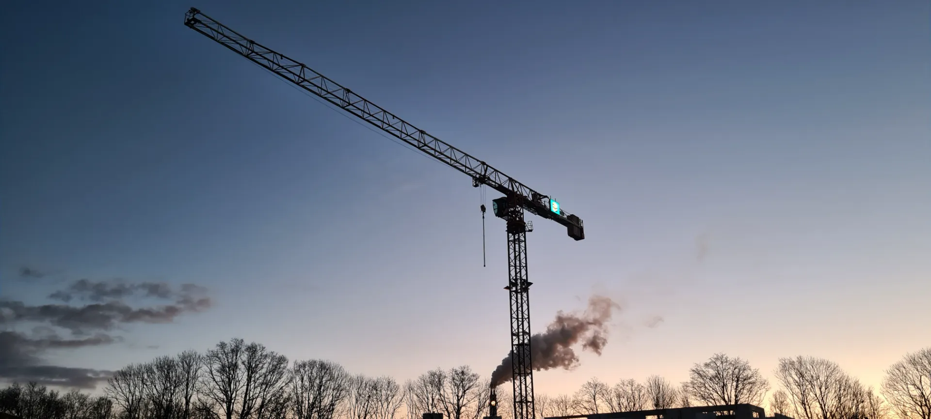 Silhouet van een torenkraan bij zonsondergang